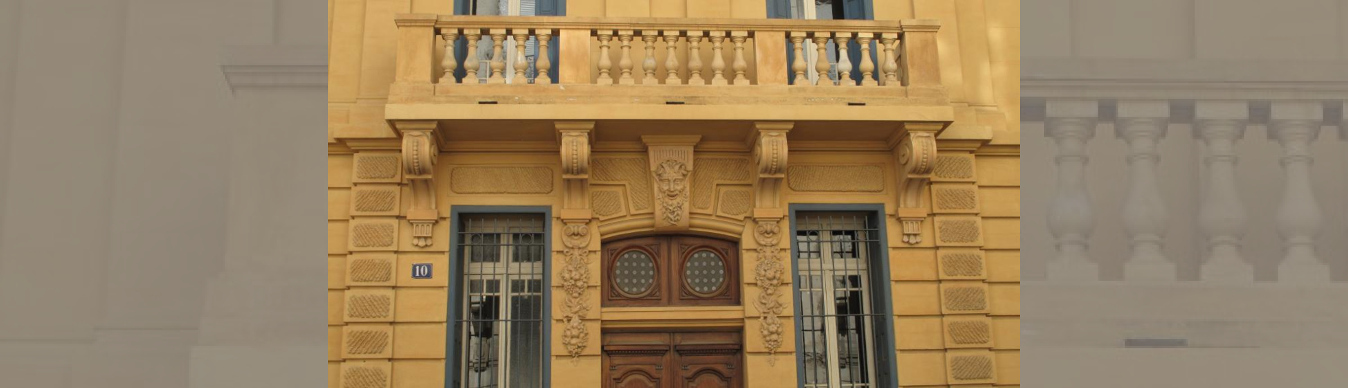 Façade peinte en ocre jaune ,balcon à balustres au 1er,guirlandes et tête de faune ornant les piedroits et linteau de l'entrée