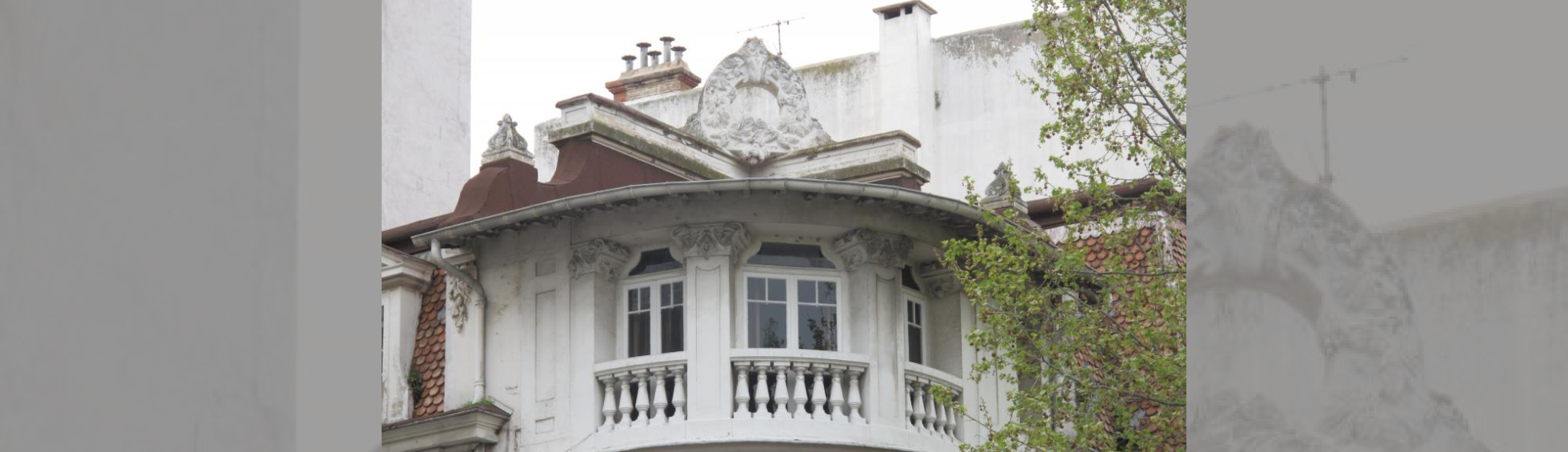  Angle du dernier niveau traité en courbe : 3 fenetres , balcons a balustres, sur le toit une couronne de branches de pin 