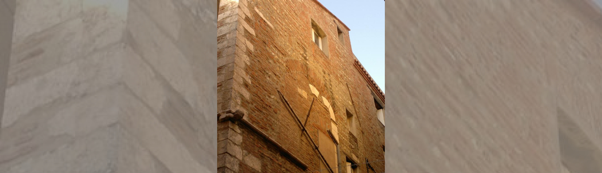Façade en briques qui a conservé à l'étage des vestiges d'une baie  à 2 arcades